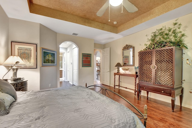 bedroom with a raised ceiling, ceiling fan, and hardwood / wood-style floors