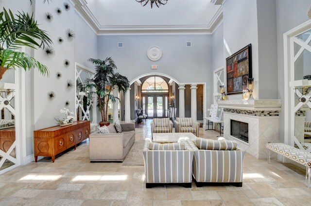 living room with crown molding, a high ceiling, and a tiled fireplace