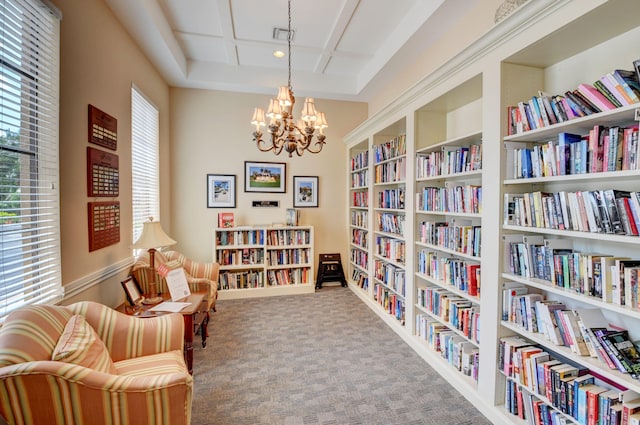 sitting room featuring carpet flooring, built in shelves, and a chandelier