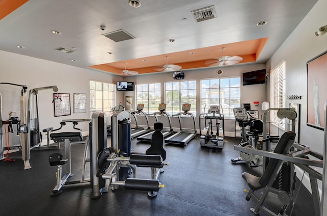 exercise room featuring ceiling fan and a tray ceiling