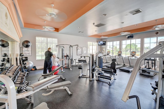 exercise room with a tray ceiling and ceiling fan