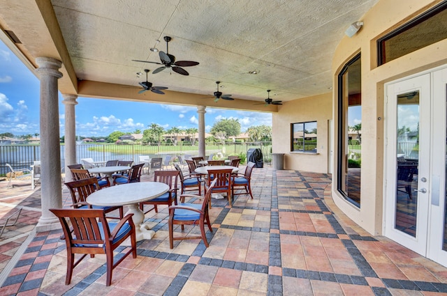 view of patio / terrace featuring ceiling fan, french doors, and a water view