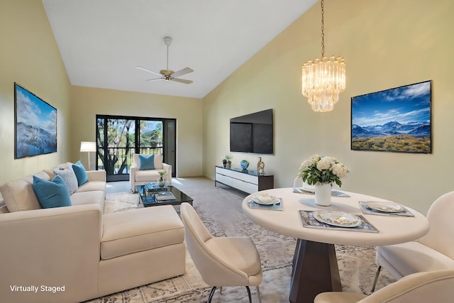 carpeted living room featuring ceiling fan with notable chandelier and high vaulted ceiling