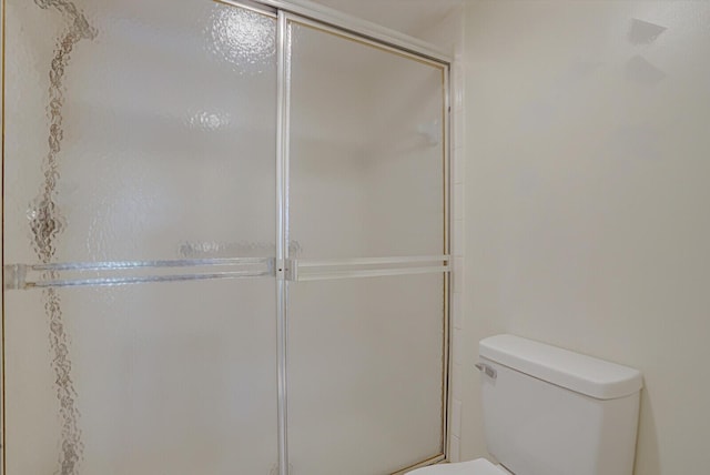 bathroom featuring a shower with shower door and toilet