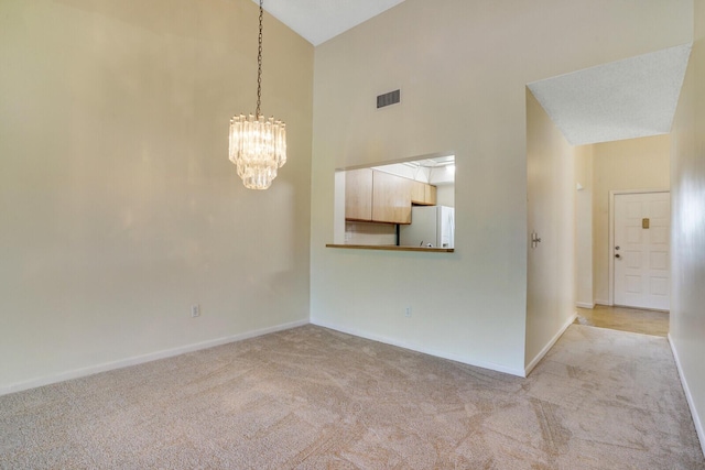 carpeted empty room with a high ceiling and a chandelier