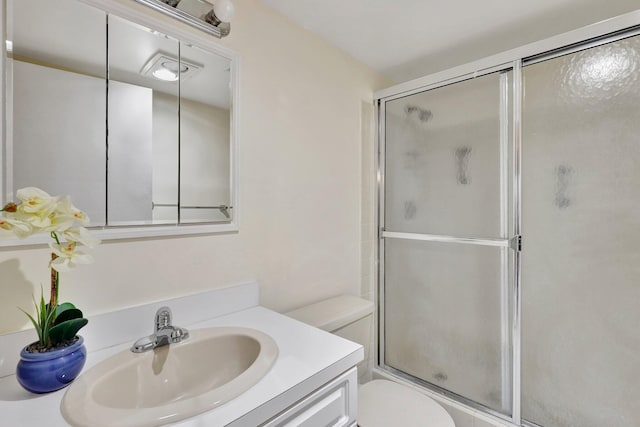 bathroom featuring vanity, toilet, and a shower with door