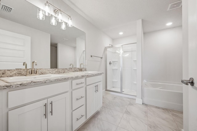 bathroom with vanity, shower with separate bathtub, and a textured ceiling