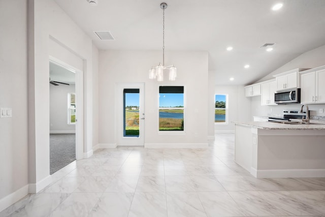 kitchen featuring light stone countertops, appliances with stainless steel finishes, vaulted ceiling, pendant lighting, and white cabinetry