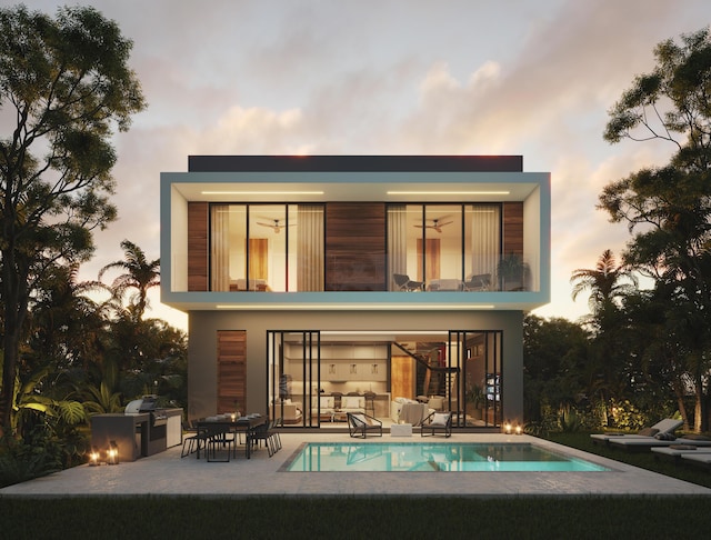 back house at dusk with an outdoor kitchen, a balcony, and a patio area