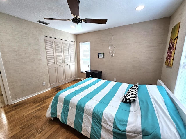 bedroom featuring ceiling fan, a closet, dark wood-type flooring, and a textured ceiling