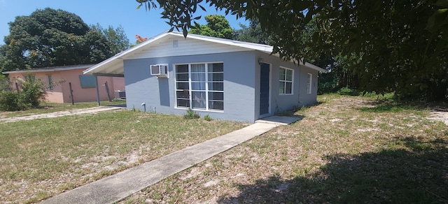 view of front of property featuring a front yard, a wall unit AC, and central AC unit