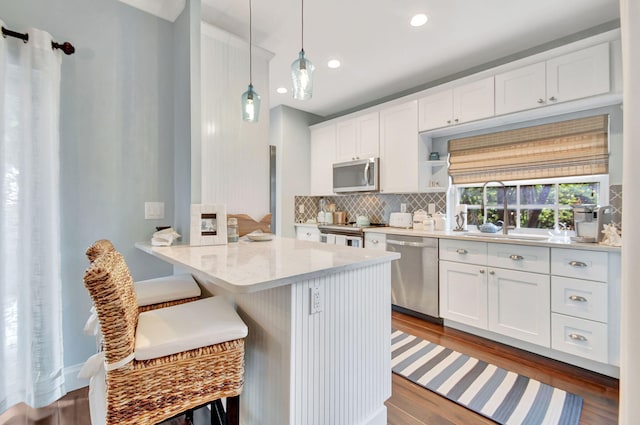 kitchen with dark wood-type flooring, white cabinets, sink, hanging light fixtures, and stainless steel appliances