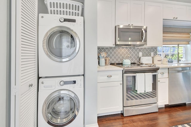 laundry area with dark hardwood / wood-style flooring and stacked washer / drying machine