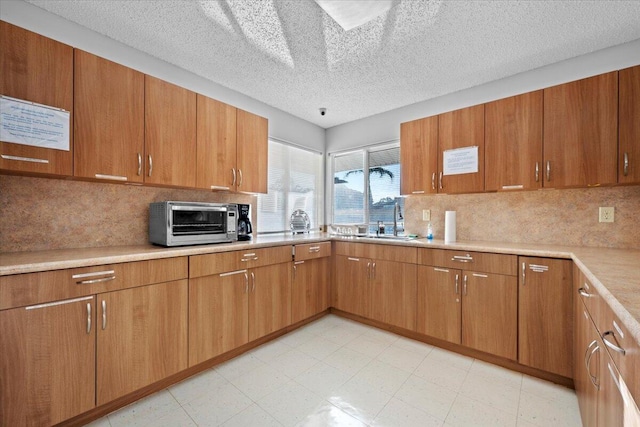 kitchen featuring sink, a textured ceiling, and backsplash