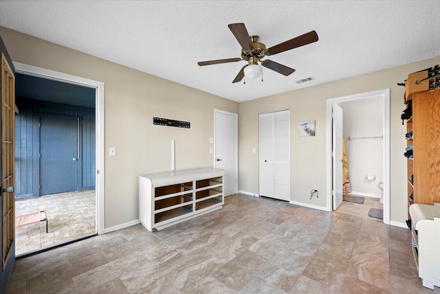 unfurnished bedroom featuring ceiling fan, a textured ceiling, and ensuite bath