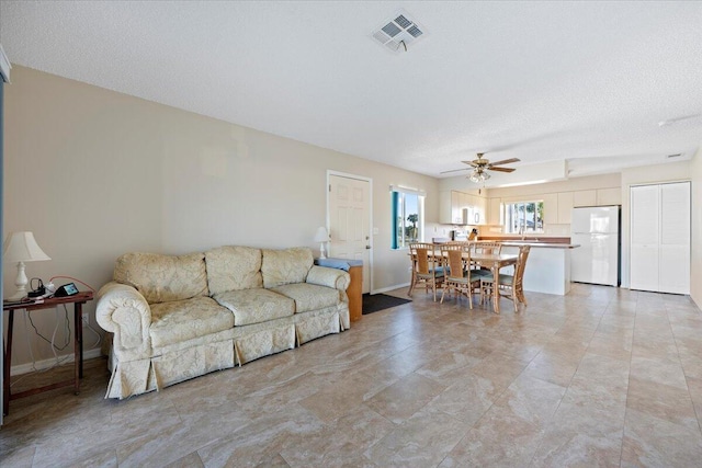 living room with ceiling fan, sink, and a textured ceiling