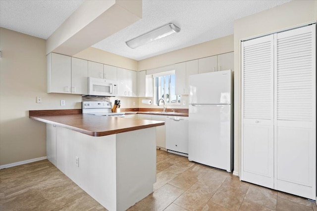 kitchen featuring white cabinetry, white appliances, and kitchen peninsula