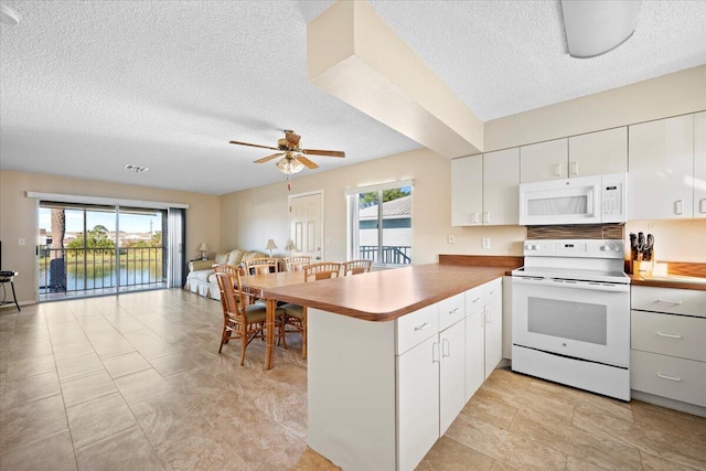 kitchen with kitchen peninsula, white appliances, white cabinetry, and plenty of natural light