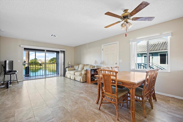 dining area with ceiling fan and a textured ceiling