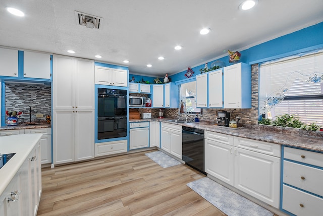 kitchen with white cabinets, decorative backsplash, light wood-type flooring, and black appliances