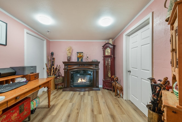 living area featuring a high end fireplace, light hardwood / wood-style floors, a textured ceiling, and ornamental molding