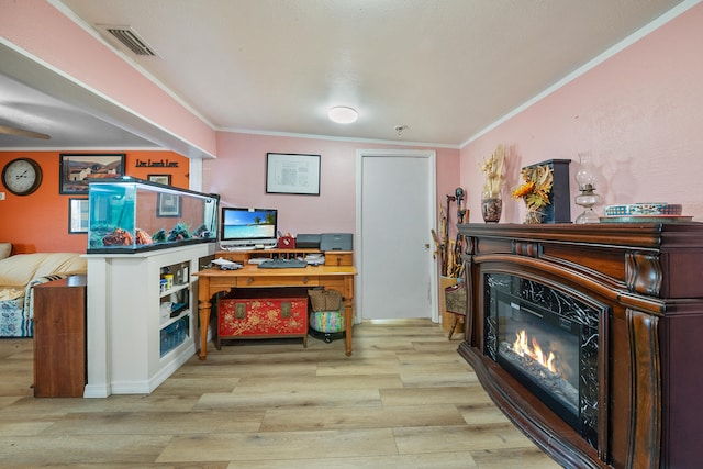 office area featuring a fireplace, light hardwood / wood-style floors, and crown molding