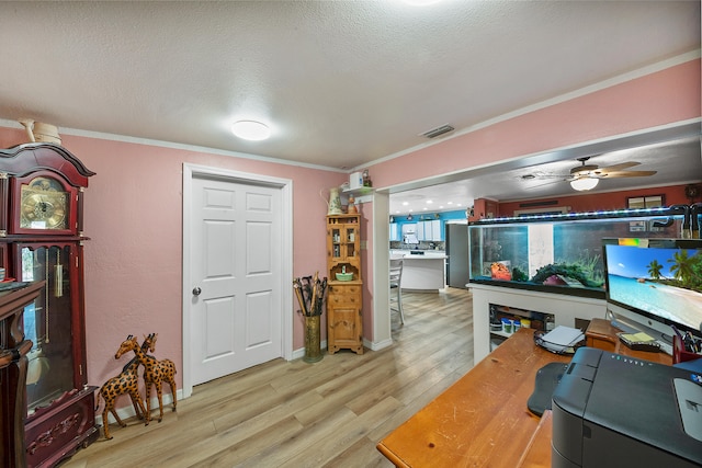 living room with a textured ceiling, light hardwood / wood-style floors, ceiling fan, and ornamental molding