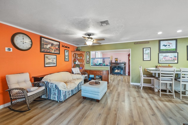 living room with ceiling fan, light hardwood / wood-style floors, crown molding, and a textured ceiling