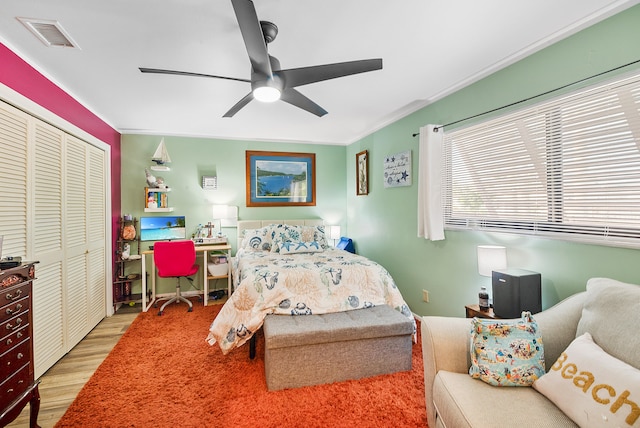 bedroom featuring hardwood / wood-style floors, a closet, ceiling fan, and crown molding