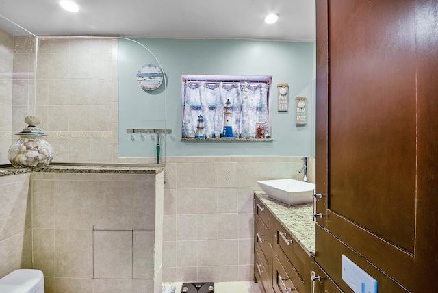 bathroom featuring a shower, vanity, tile walls, and toilet