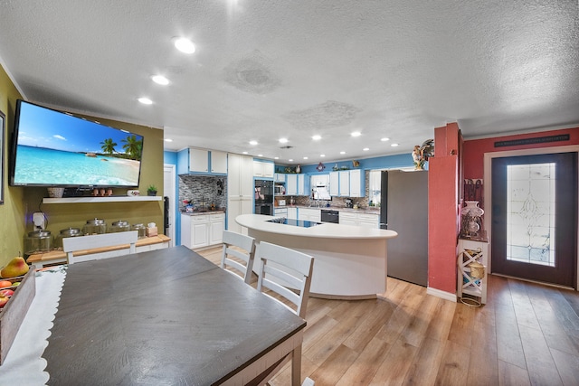 kitchen with decorative backsplash, a textured ceiling, black appliances, light hardwood / wood-style flooring, and white cabinets