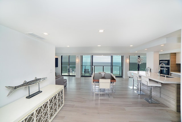 dining space with a water view, sink, and light hardwood / wood-style floors