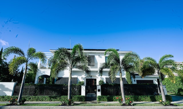 view of front of home with a fenced front yard, stucco siding, a balcony, and a gate