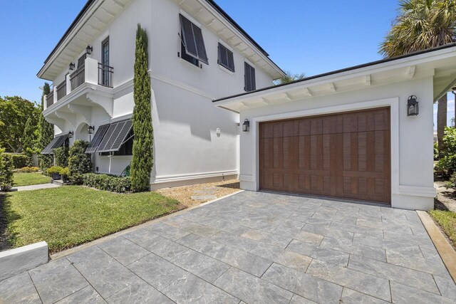 view of property exterior featuring a yard, decorative driveway, and stucco siding