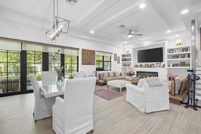 living room featuring light wood finished floors, a glass covered fireplace, visible vents, and recessed lighting