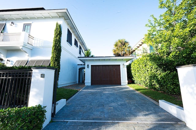 view of front of property with a balcony, fence, driveway, stucco siding, and a garage