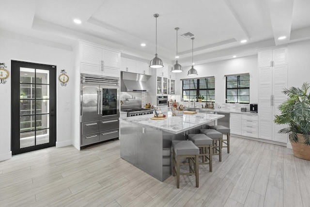 kitchen with a breakfast bar, a tray ceiling, white cabinetry, and extractor fan