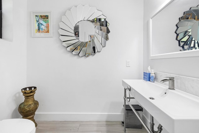 bathroom with hardwood / wood-style flooring, toilet, and sink