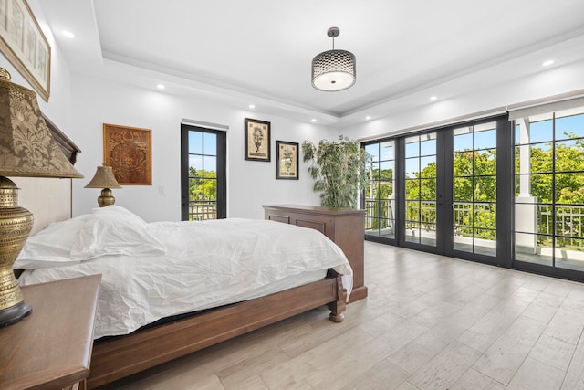 bedroom featuring french doors, light wood-type flooring, access to outside, and a tray ceiling