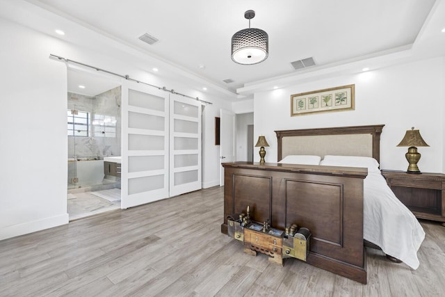 bedroom featuring recessed lighting, visible vents, light wood-style flooring, and a barn door