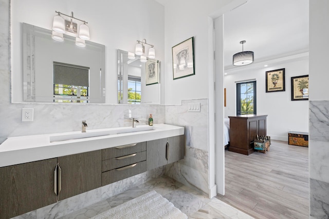 bathroom with hardwood / wood-style floors, vanity, a wealth of natural light, and tile walls