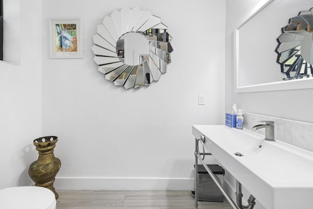 bathroom featuring toilet, baseboards, and a sink