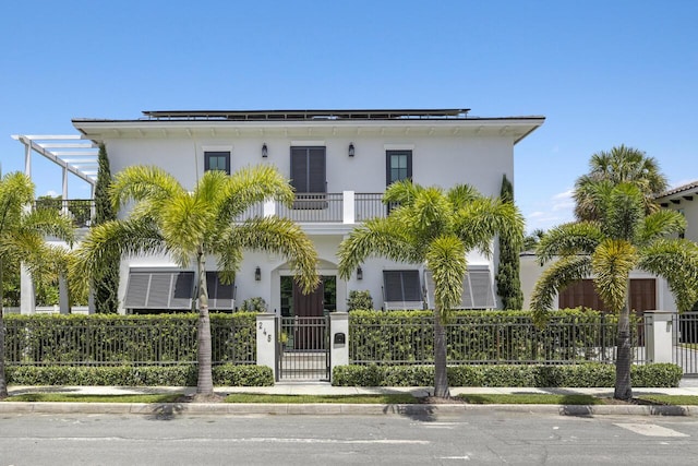 view of front facade with a balcony, a gate, a fenced front yard, and stucco siding