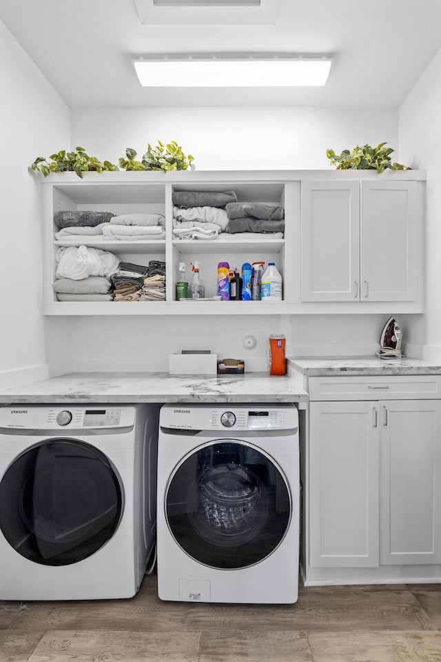 washroom with washer and dryer, cabinet space, and light wood-style flooring