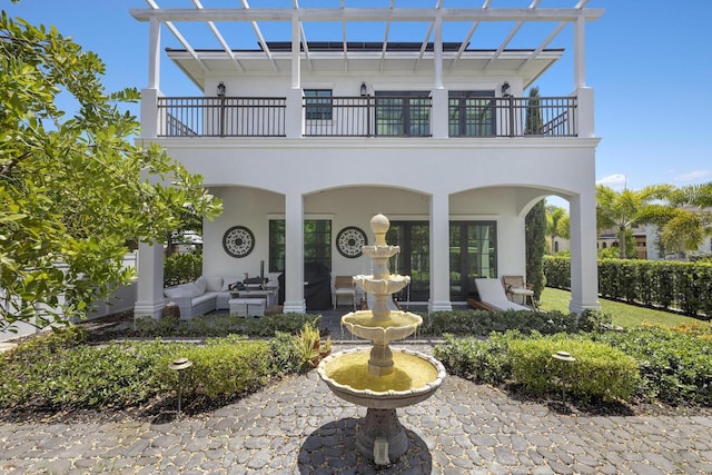 rear view of property featuring an outdoor hangout area, a balcony, and stucco siding