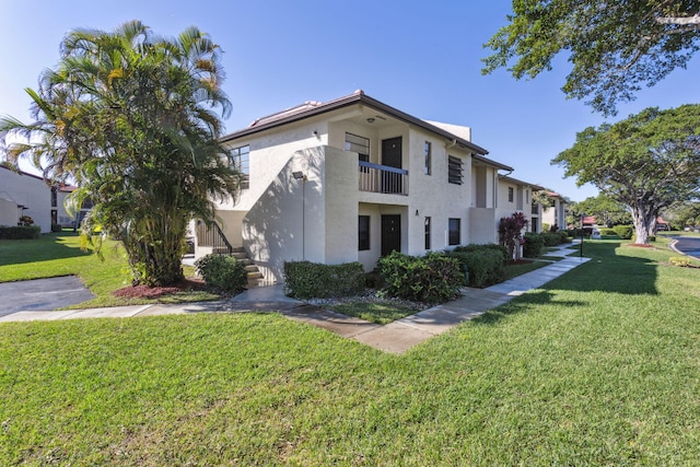 view of side of home featuring a balcony and a lawn