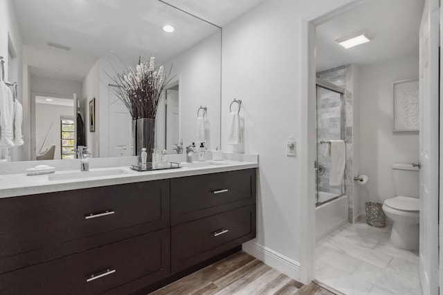 full bathroom with vanity, toilet, bath / shower combo with glass door, and hardwood / wood-style flooring