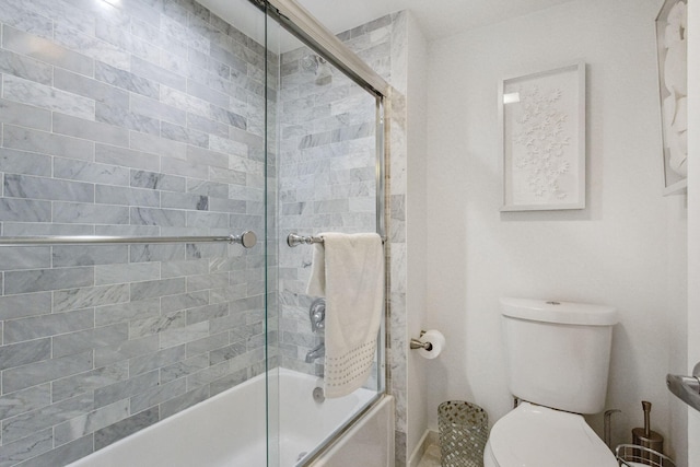 bathroom with toilet and combined bath / shower with glass door