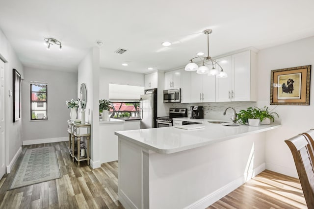 kitchen with sink, white cabinets, decorative light fixtures, kitchen peninsula, and stainless steel appliances