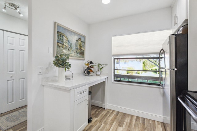 interior space featuring light stone counters, white cabinetry, stainless steel appliances, and light wood-type flooring